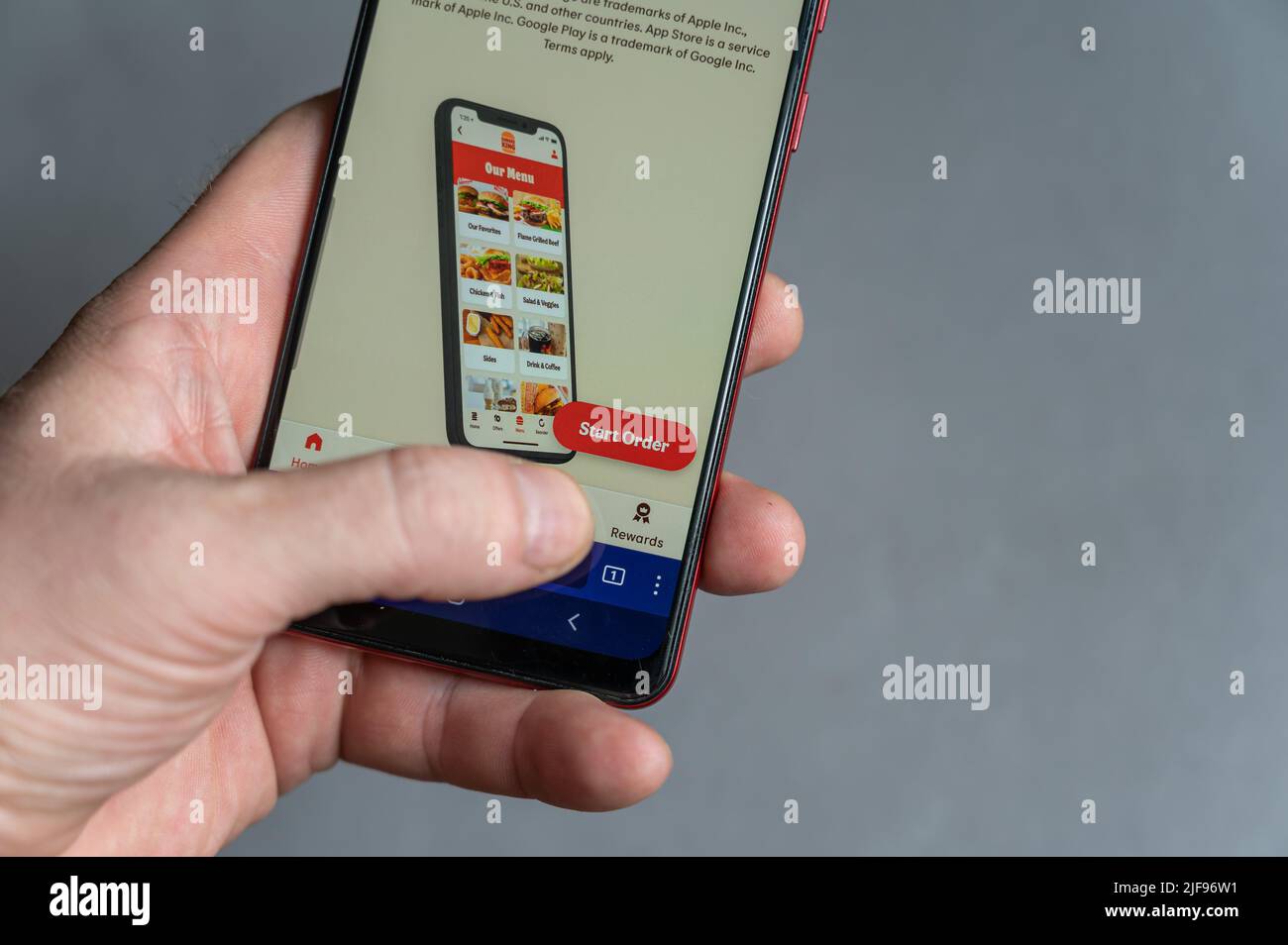 Männliche Hand hält Smartphone mit BURGER KING Webseite auf dem Bildschirm. Amerikanische Fast-Food-Restaurantkette. Der Hauptsitz befindet sich in Miami-Dade County, Florida. Stockfoto