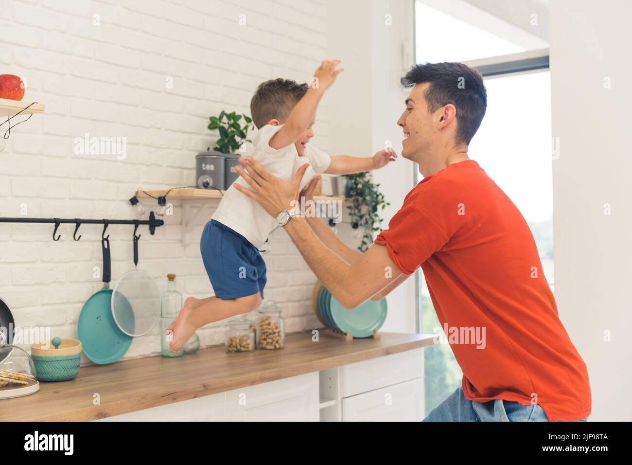 Ein Vater fängt seinen Sohn, der aus dem Schrank springt, glückliche Familie. Hochwertige Fotos Stockfoto