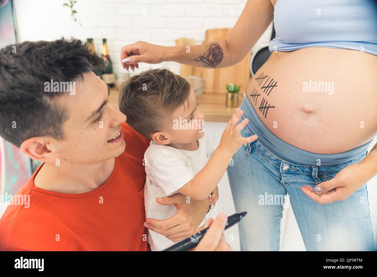 Kleines Kind zählt Wochen seiner Schwangeren Mutter mit Eltern, glückliches Familienkonzept. Hochwertige Fotos Stockfoto