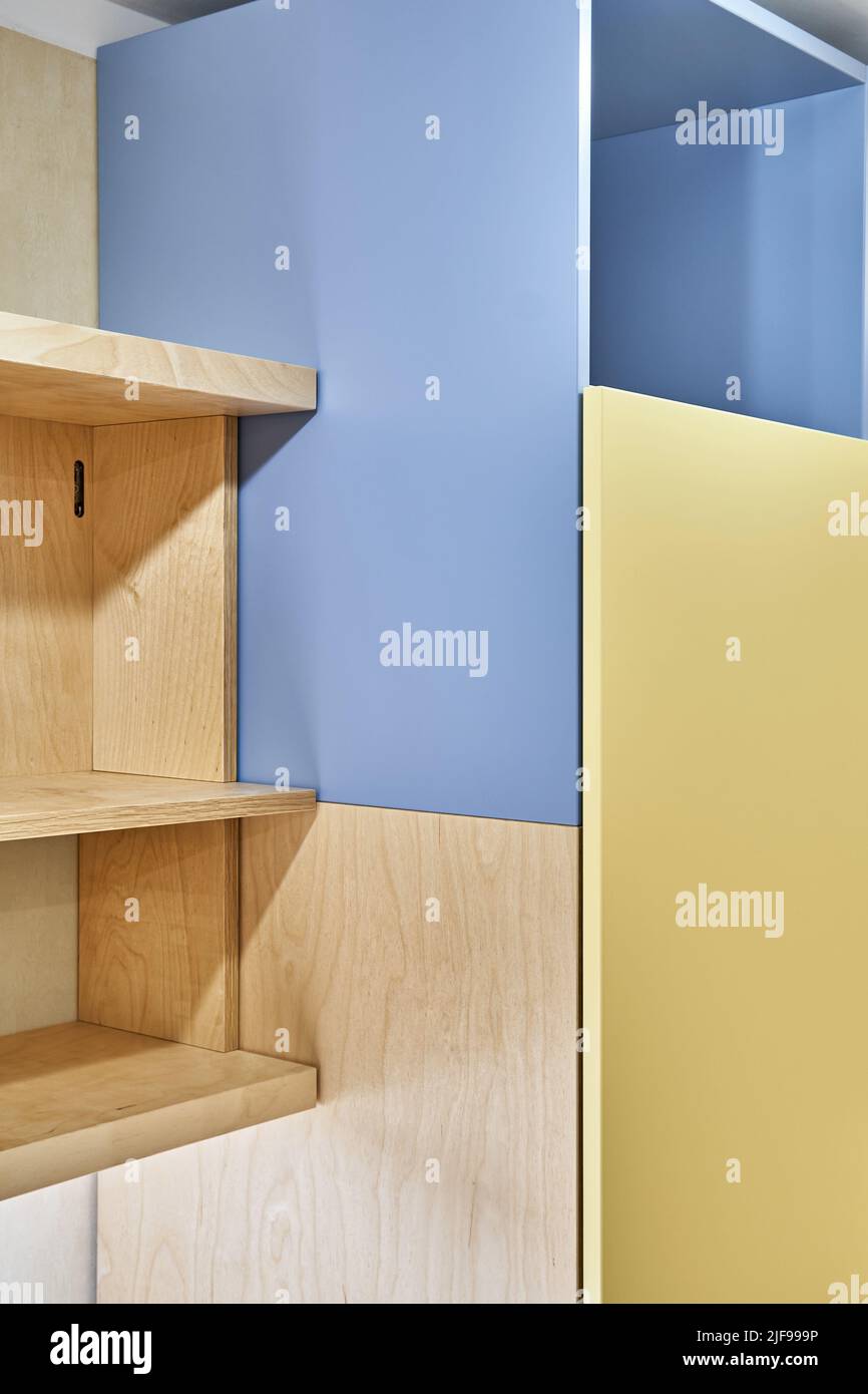 Fragment von Sperrholz Bücherregalen und gelb-blauen Sperrholzschrank zu Hause. Moderne Haushaltsmöbel für Schlafzimmer Innenansicht Stockfoto