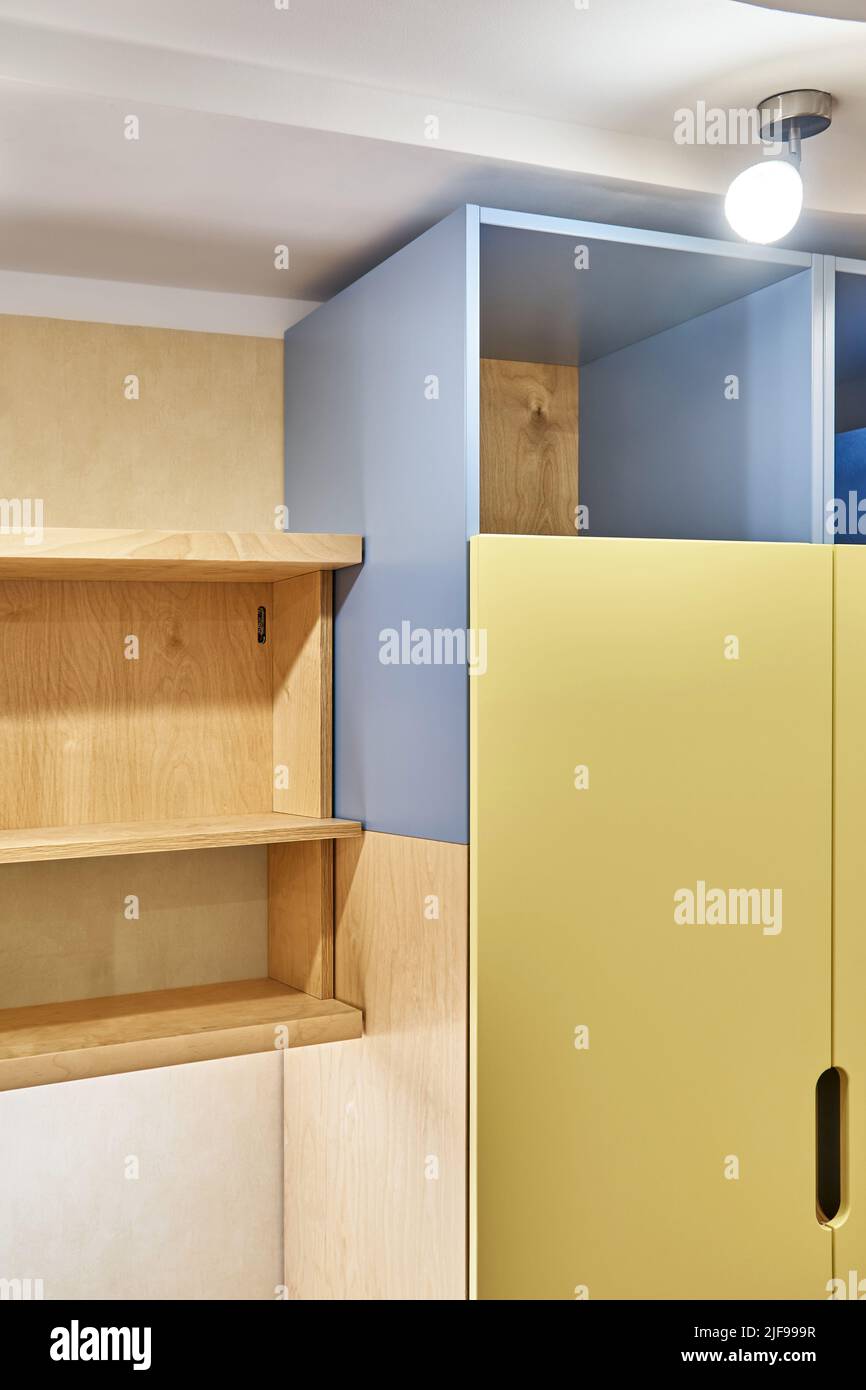 Fragment von Sperrholz Bücherregalen und gelb-blauen Sperrholzschrank zu Hause. Moderne Haushaltsmöbel für Schlafzimmer Innenansicht Stockfoto