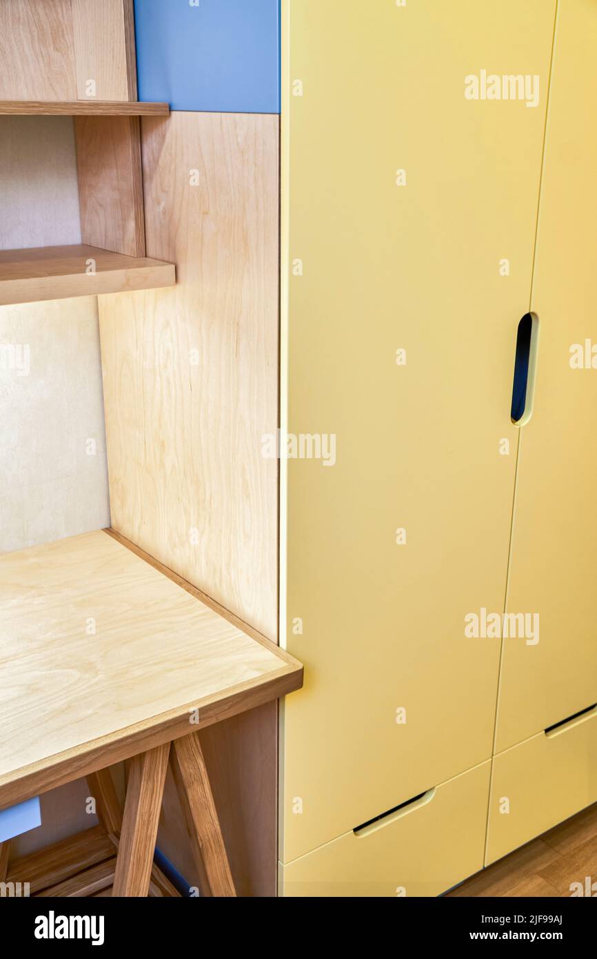 Fragment von Kindertisch mit Schrank aus Sperrholz und massiver Eiche steht in der Nähe von gelben Schrank. Holzmöbel für Schlafzimmer Innenansicht Stockfoto