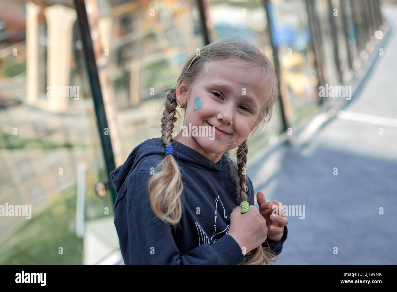 Mädchen mit gemalter Ukraine Flagge gelb und blau. Beendet den Krieg und die Macht der Ukraine, den Patriotismus. Kinder unterstützen die Ukraine. Kein Krieg. Betet für die Ukraine. Stockfoto