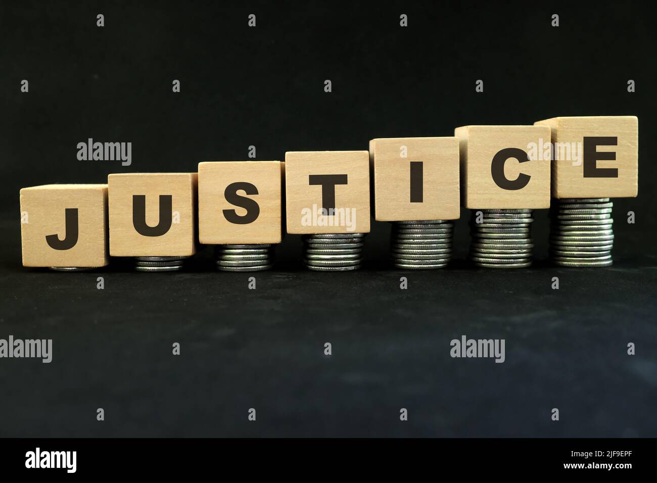 Hoher Preis für Gerechtigkeit, Ungleichheit und Gerechtigkeit für das reiche Konzept. Holzblöcke mit einem wachsenden Münzstapel auf dunkelschwarzem Hintergrund. Stockfoto