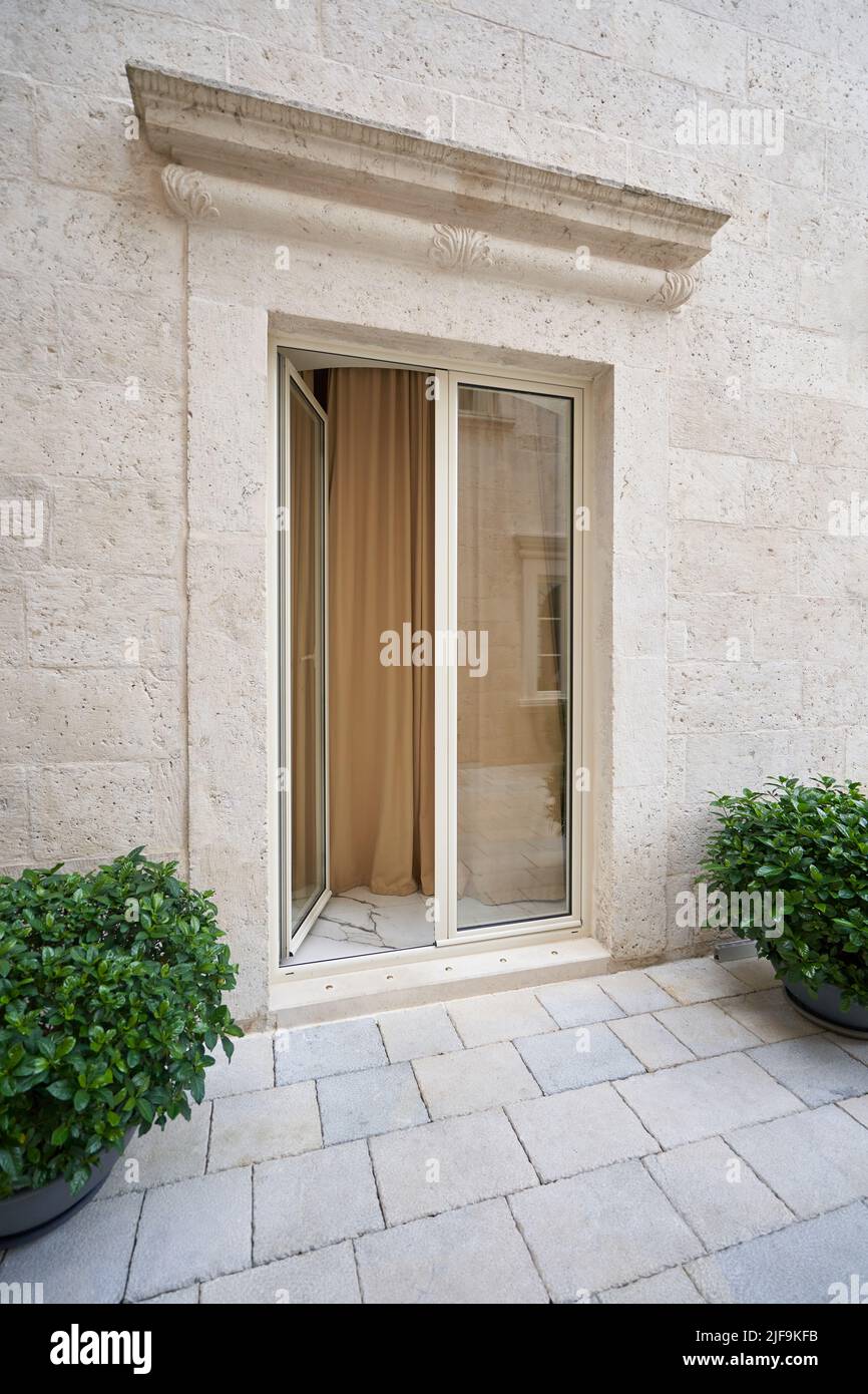 Beige elegante Eingangstür mit Glas an der beigefarbenen Steinwand. Stockfoto