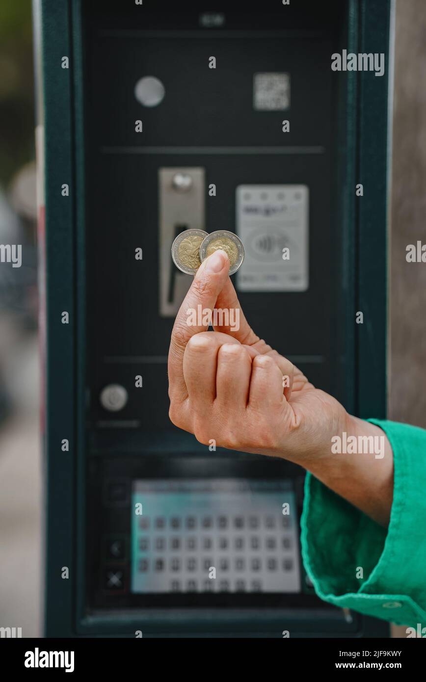 Frau, die Euro-Münzen vor dem Parkplatz hält. Stockfoto