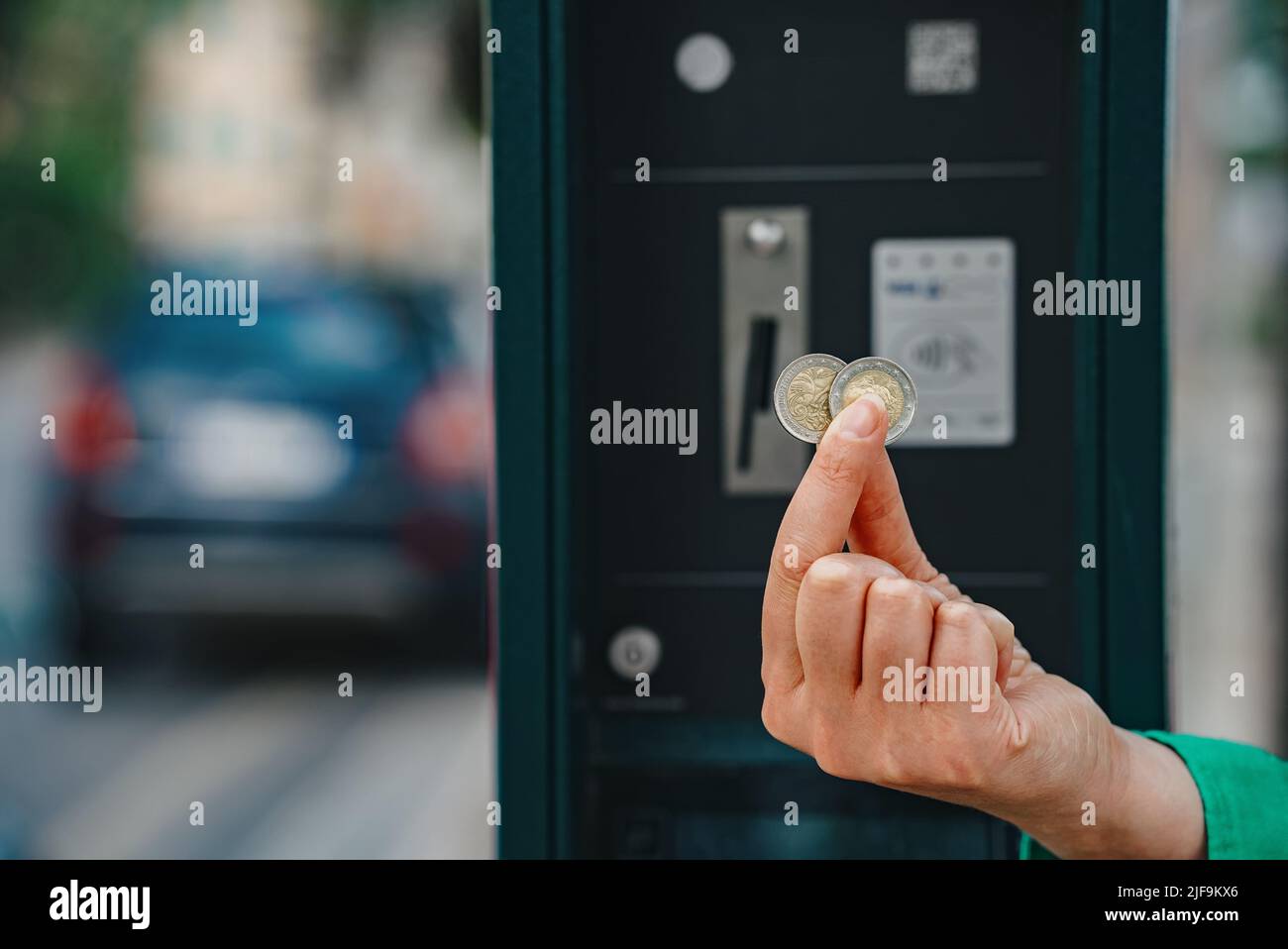 Frau, die Euro-Münzen vor dem Parkplatz hält. Stockfoto
