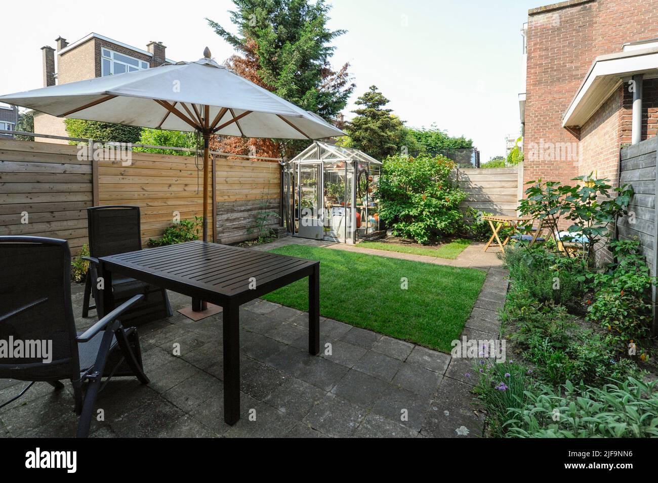 Schöner Garten in den Niederlanden, mit Gartenmöbeln und Sonnenschirm Stockfoto