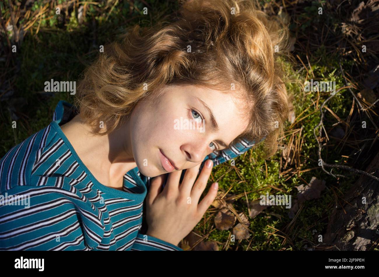 Schöne junge Frau 18 Jahre alt liegt auf dem grünen Moos im Wald, genießen das Sonnenlicht. Outdoor-Erholung, die Lebenskraft der Erde. hallo Stockfoto
