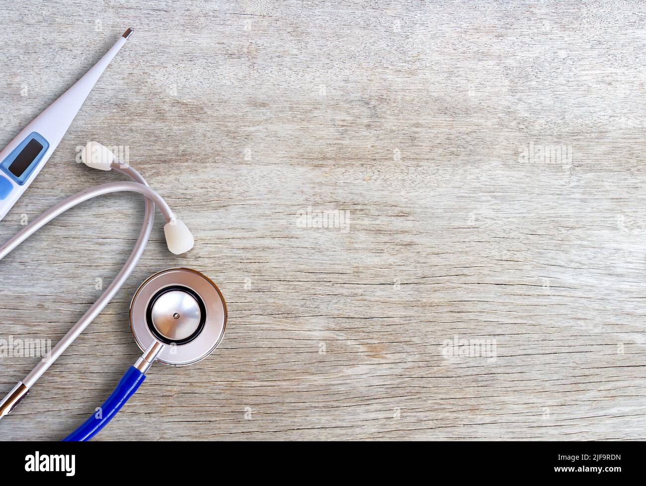 Medizinische und gesunde Geräte. Blaue Stethoskope und Thermometer auf Holztisch für medizinische Inhalte.Draufsicht mit Kopierraum für Design. Unternehmenszustand und Stockfoto