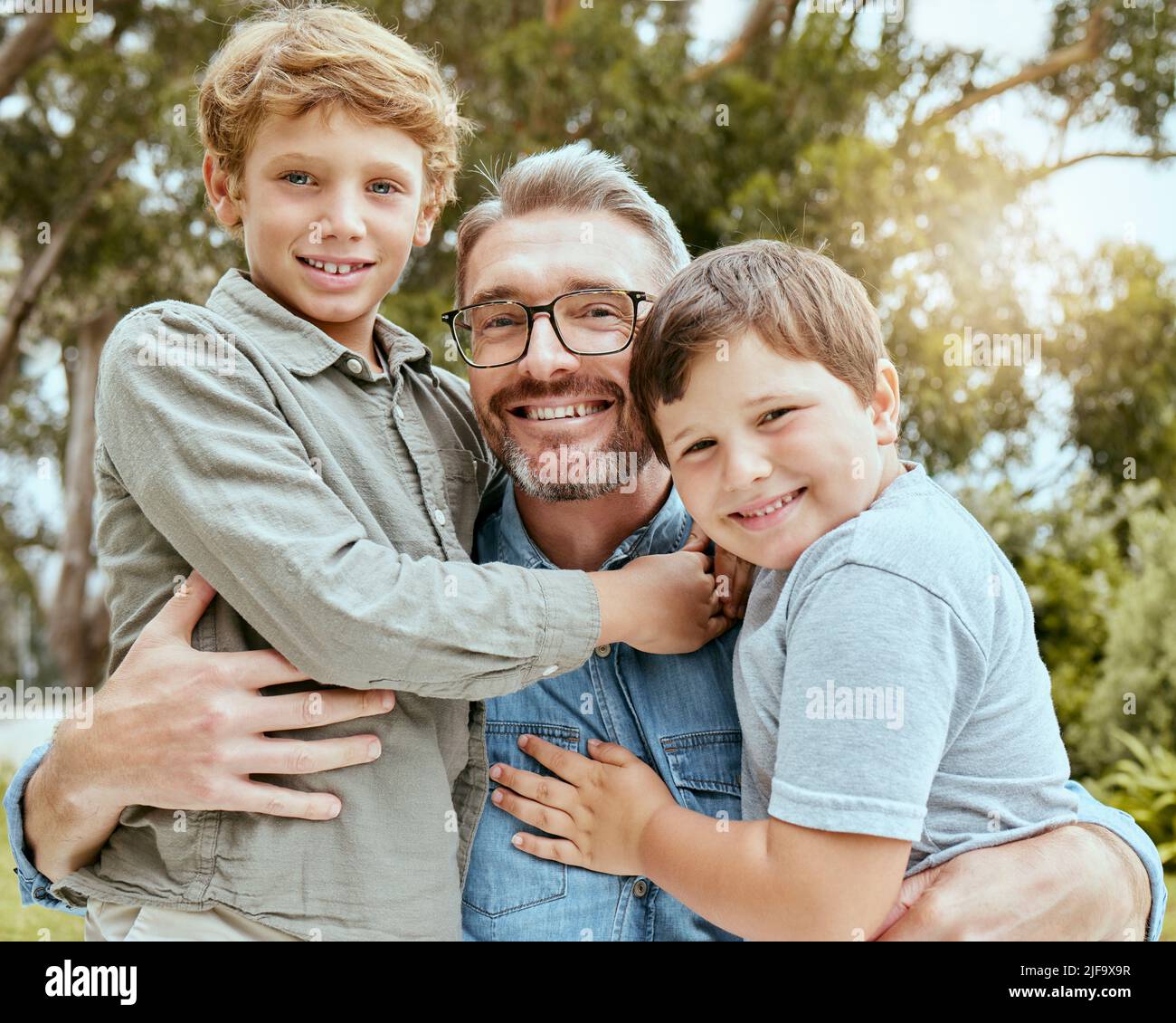 Ein glücklicher kaukasischer Alleinerziehender genießt es, mit seinen Söhnen im Hinterhof zu spielen. Lächelnde Familie von drei Männern, die sich nur in einem Garten draußen amüsieren Stockfoto