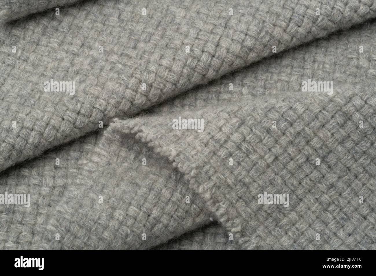 Strukturierter Stoffhintergrund. Eine graue Wolldecke in Falten. Stockfoto