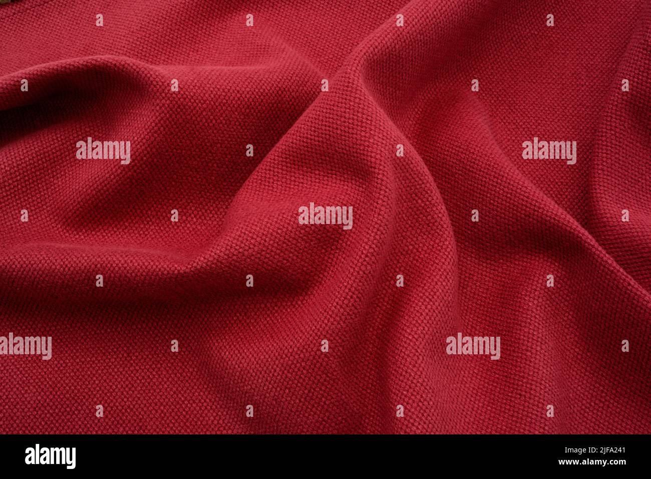 Strukturierter Stoffhintergrund. Ein roter geraffter Leinenstoff. Stockfoto
