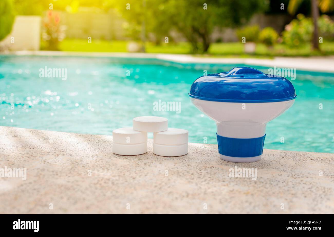 Ein Schwimmbadfloat und Chlortabletten am Rand eines Schwimmbads. Tabletten mit Chlorspender für Schwimmbäder. Chlortabletten mit Dosierung Stockfoto