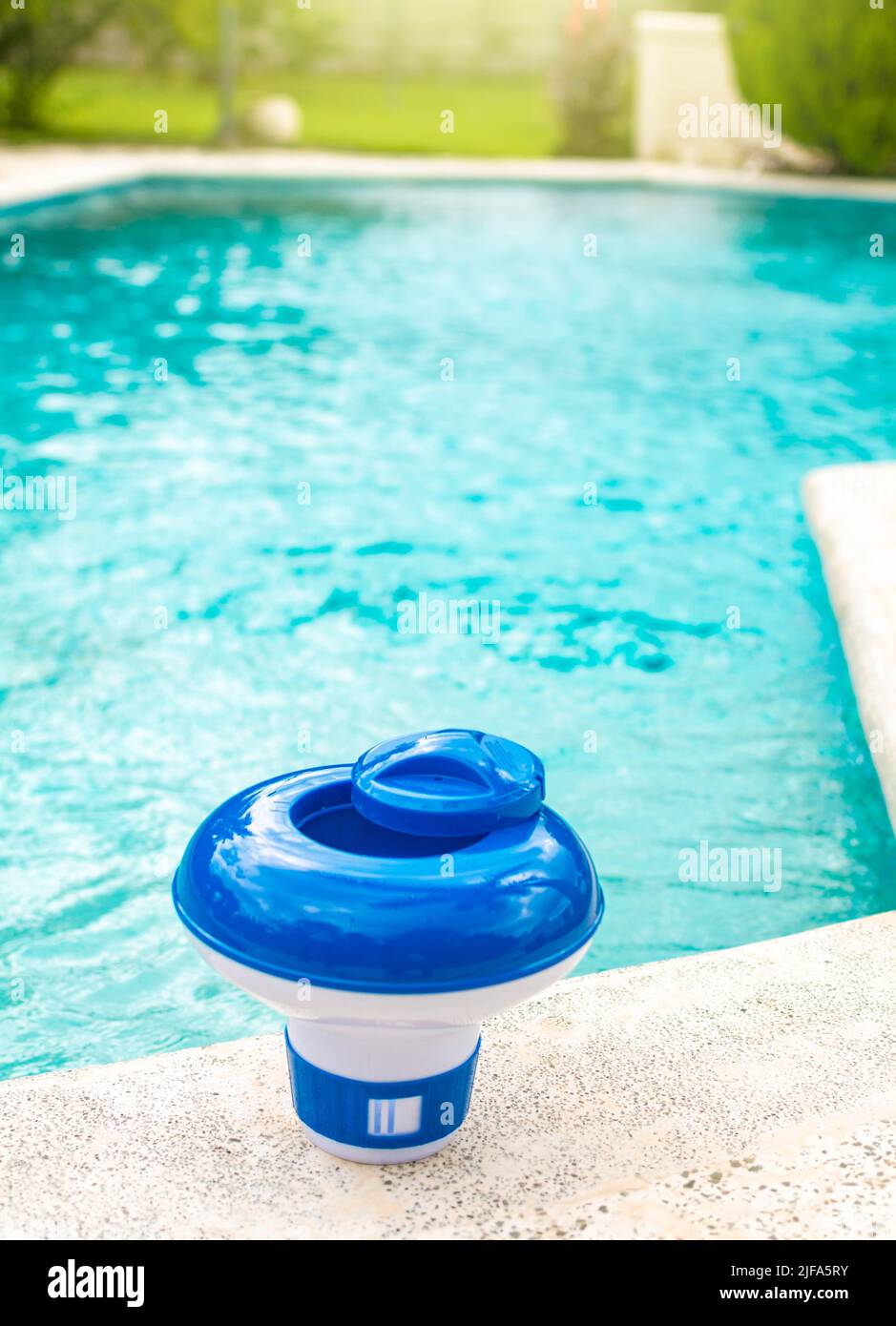 Ein Chlor schwimmt am Rand eines Schwimmbades. Ein Chlorspender für Schwimmbäder mit blauem Wasser im Hintergrund. Dosierschwimmbad zum Schwimmen Stockfoto