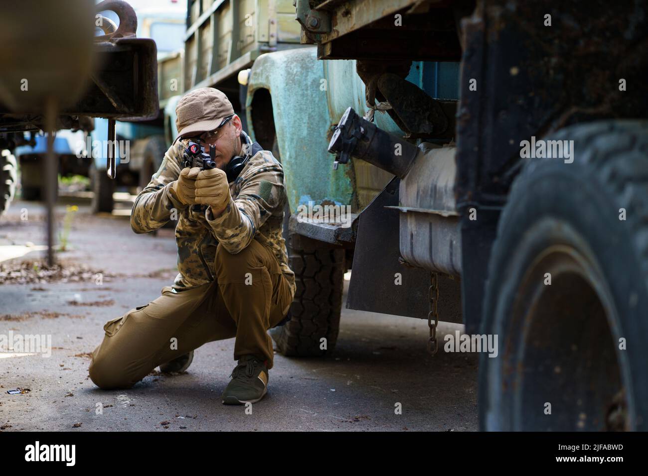 Junger Mann in taktischem Trainingskurs. Outdoor-Aufnahmebereich. Privater militärischer Auftragnehmer bei taktischem Schulungskurs. Defensive Taktik Shooter Kurs, Mann mit einer Waffe in Militäruniform. Stockfoto