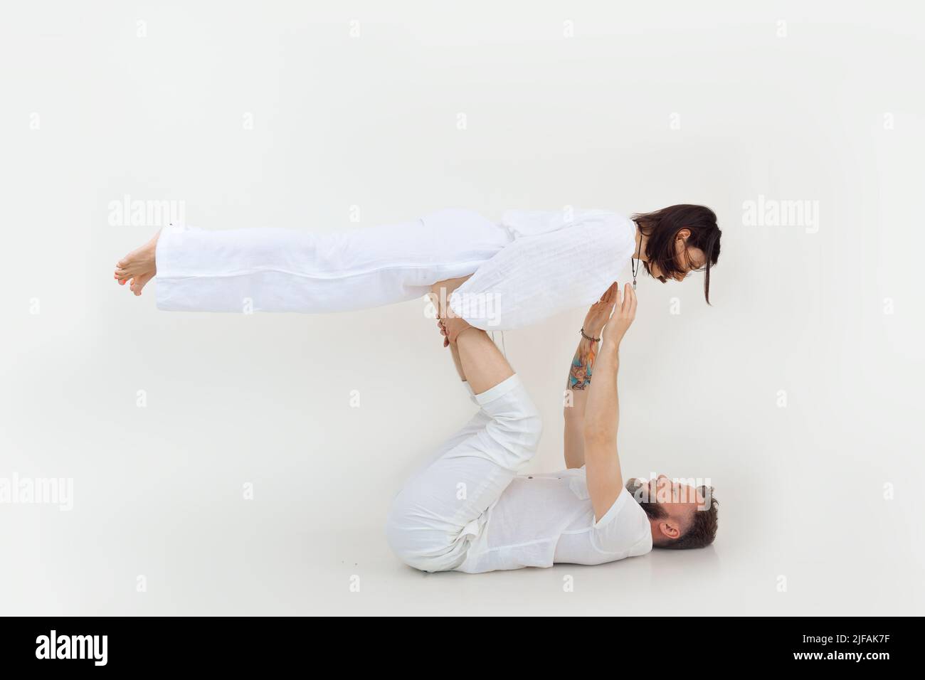 Sportliche und sportliche Familie von Mann und Frau, die Yoga-Übungen praktizieren, Männer halten Frau in der Luft. Gesunder Lebensstil Stockfoto