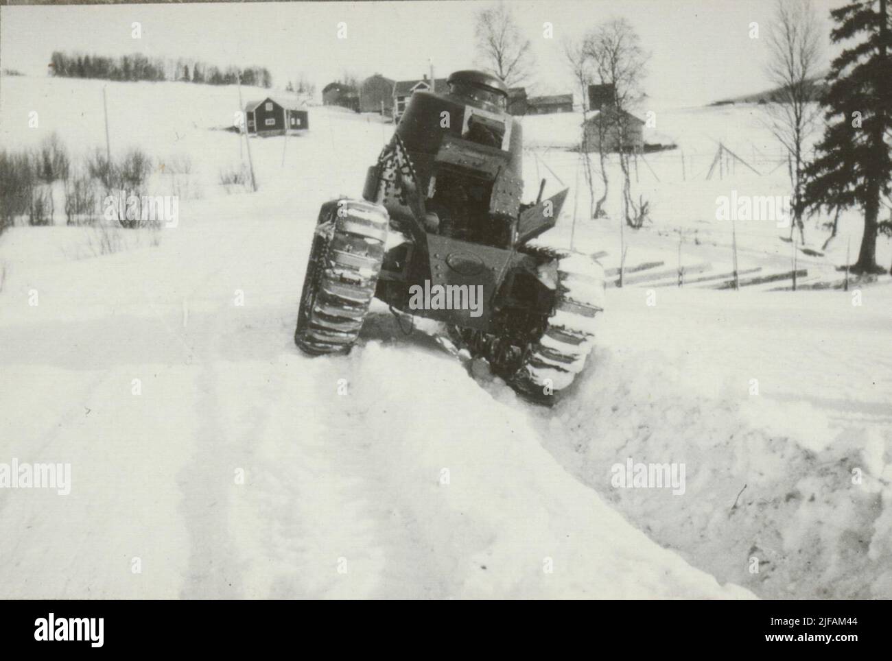Das Fahrerhaus im Tank der Marke Renault auf einer winterlichen Landstraße. Im Hintergrund eine Reihe von Holzgebäuden. Stockfoto