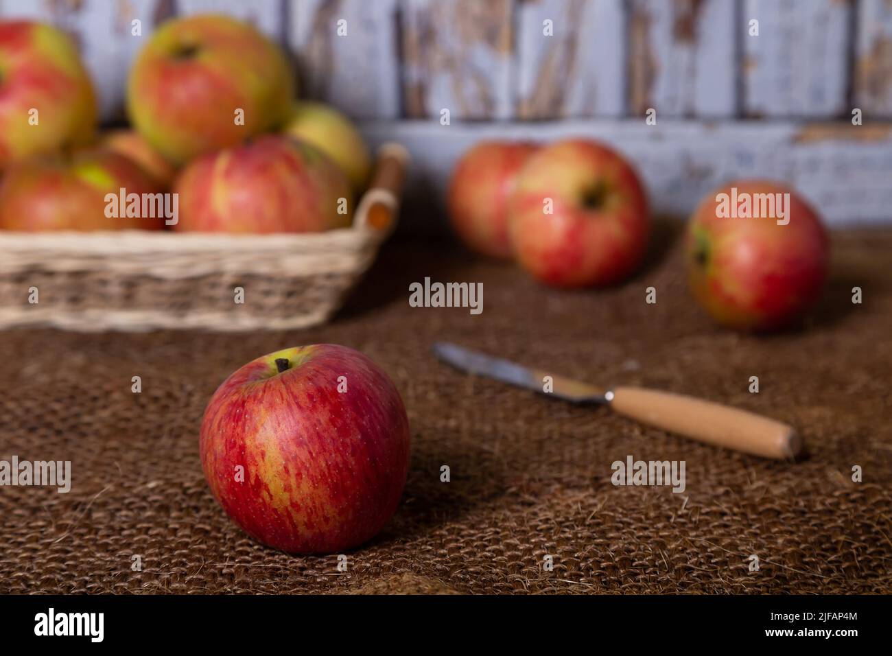 Reife Äpfel auf Sackleinen und in einem Korb. Rustikaler Stil, Nahaufnahme. Stockfoto