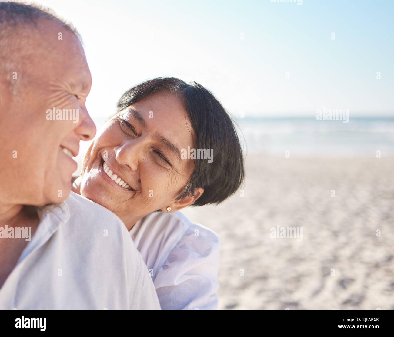 Liebevolles reifes gemischtes Rennpaar, das einen intimen Moment am Strand teilt. Älterer Ehemann und Ehefrau genießen einen Sommertag am Meer. Sie lieben es Stockfoto