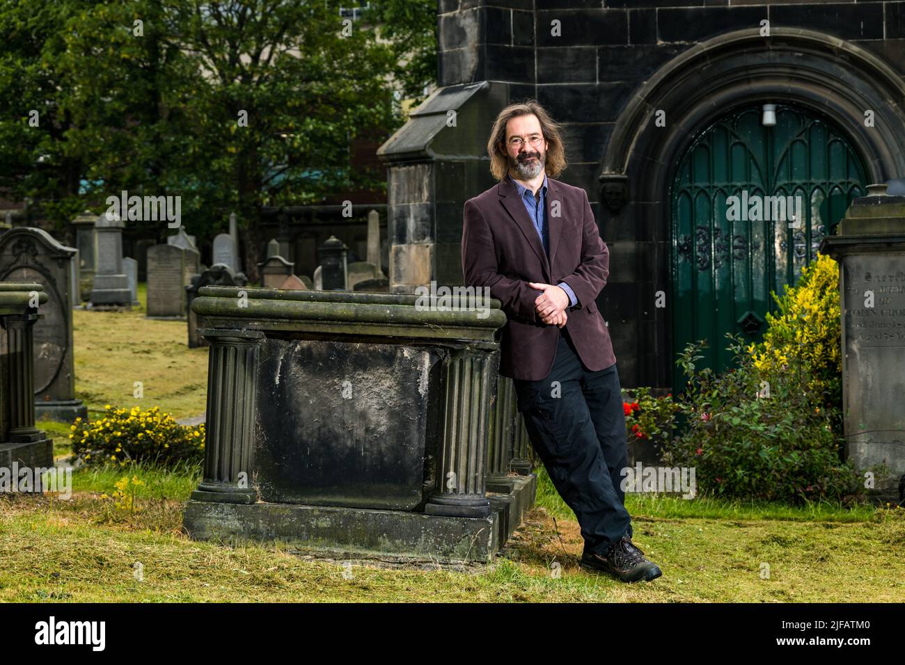 Der schottische Kriminalschriftsteller James Oswald auf dem Friedhof der South Leith Parish Church mit einem alten Grabstein, Edinburgh, Schottland, Großbritannien Stockfoto