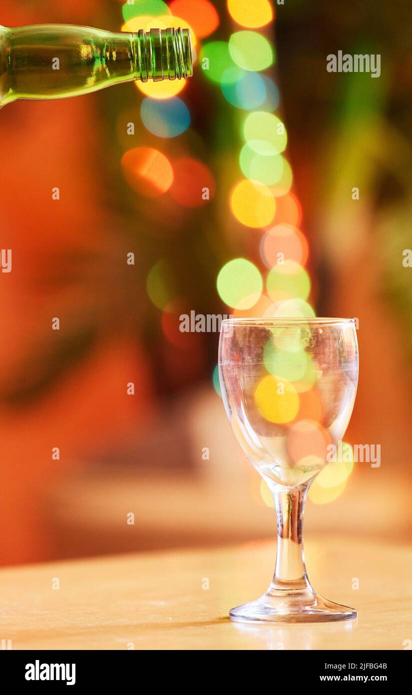 Nahaufnahme eines Glases vor einem lebhaften Bokeh-Hintergrund. Ein transparentes Glas auf einem Tisch. Geschirr, das zum Genuss alkoholischer Getränke wie Bier oder verwendet wird Stockfoto