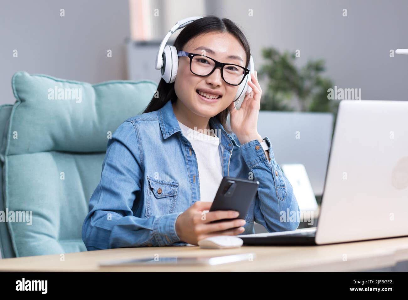 Porträt einer jungen asiatischen Studentin, die online am Laptop studiert und dabei einen Laptop und Kopfhörer benutzt, um den Online-Kurs zu hören. Stockfoto