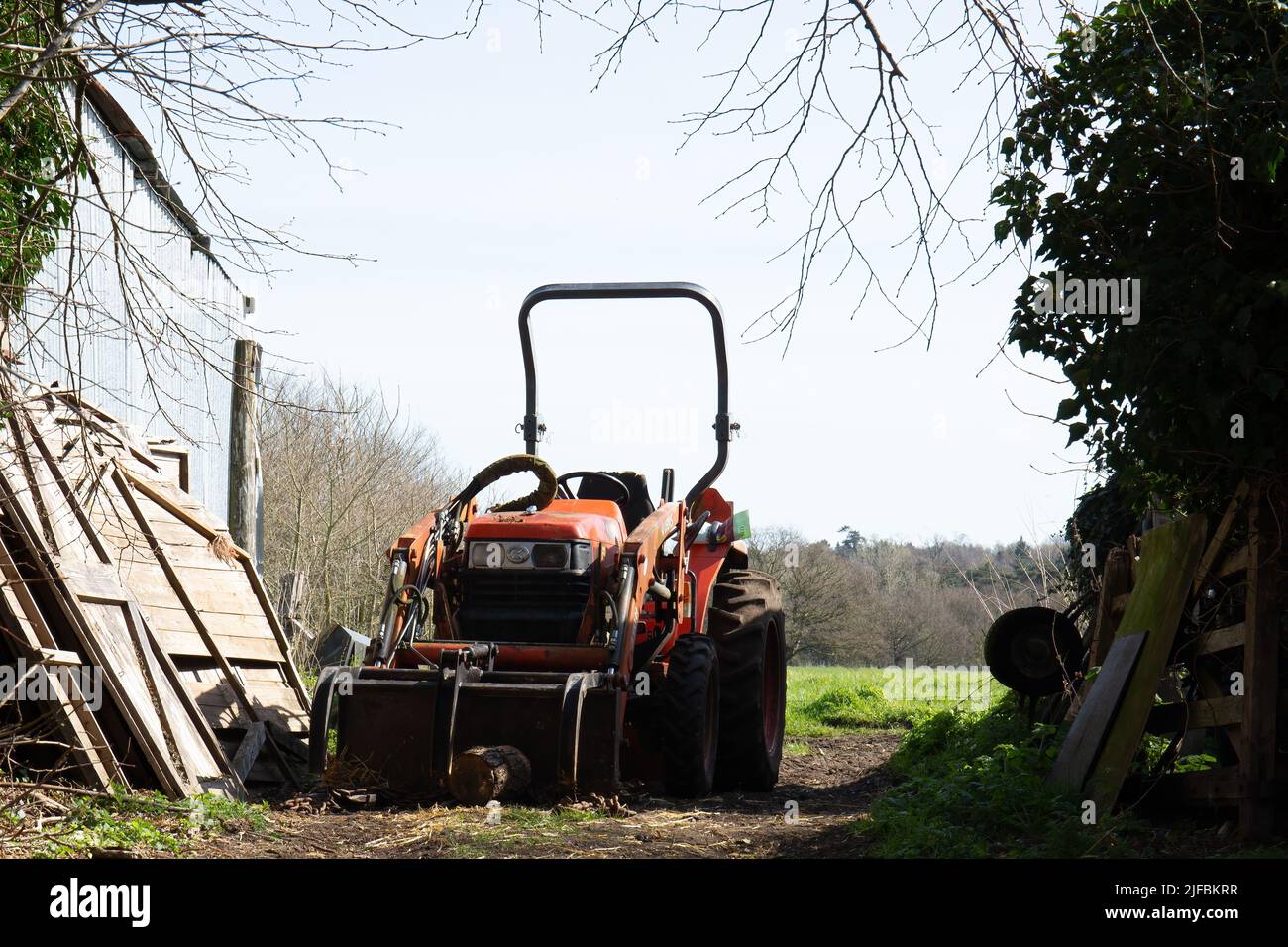 Ein roter Traktor parkte im Tor neben einer Scheune Stockfoto