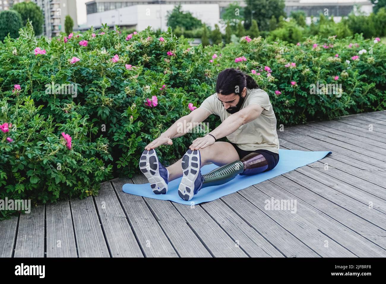 Fit Mann mit körperlicher Behinderung beim Aufwärmen Stretching vor dem Training Routine im Freien - Fokus auf Beinprothese Stockfoto