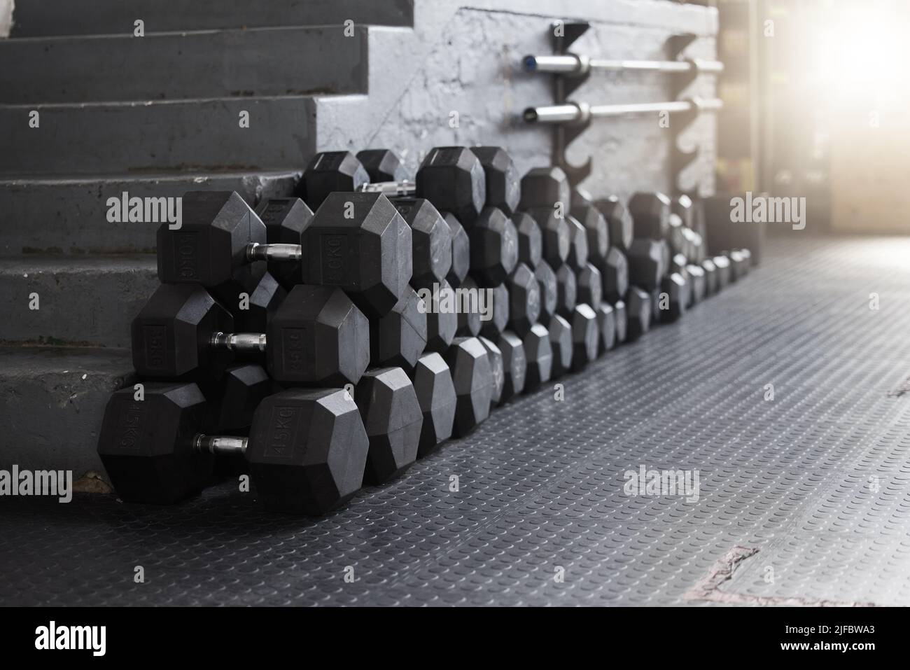 Nahaufnahme einer Gruppe von Gewichten im Fitnessstudio auf dem Boden in einem leeren Gesundheits- und Sportclub. Makroansicht der Hanteln Langhantelgewichte in einem dunklen Fitnessraum Stockfoto