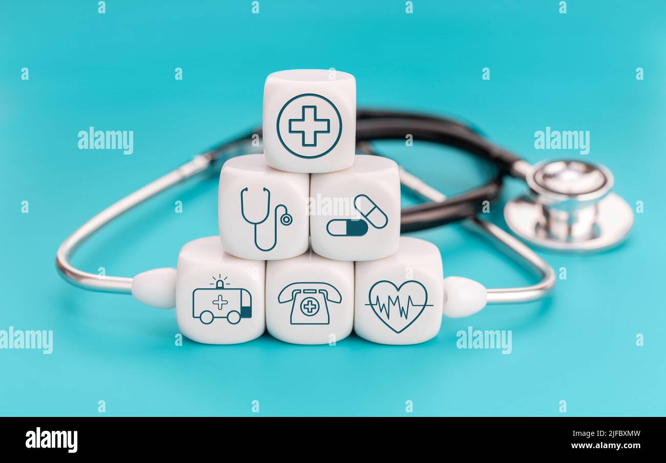 Konzept der Krankenversicherung. Medizinische Symbole auf würfelförmigen Blöcken und Stethoskop auf blauem Hintergrund Stockfoto