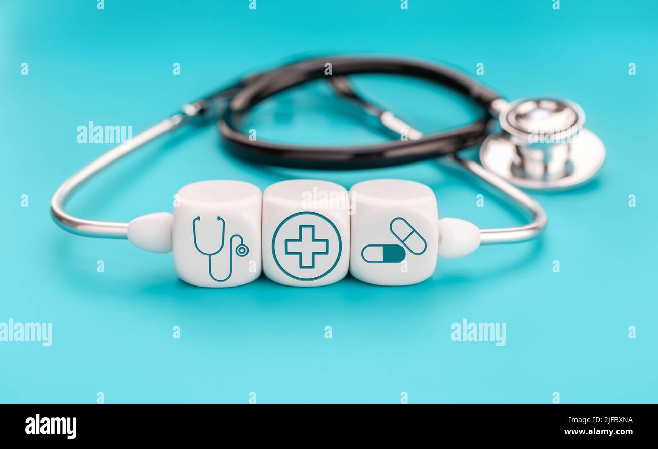 Konzept der Krankenversicherung. Medizinische Symbole auf würfelförmigen Blöcken und Stethoskop auf blauem Hintergrund Stockfoto
