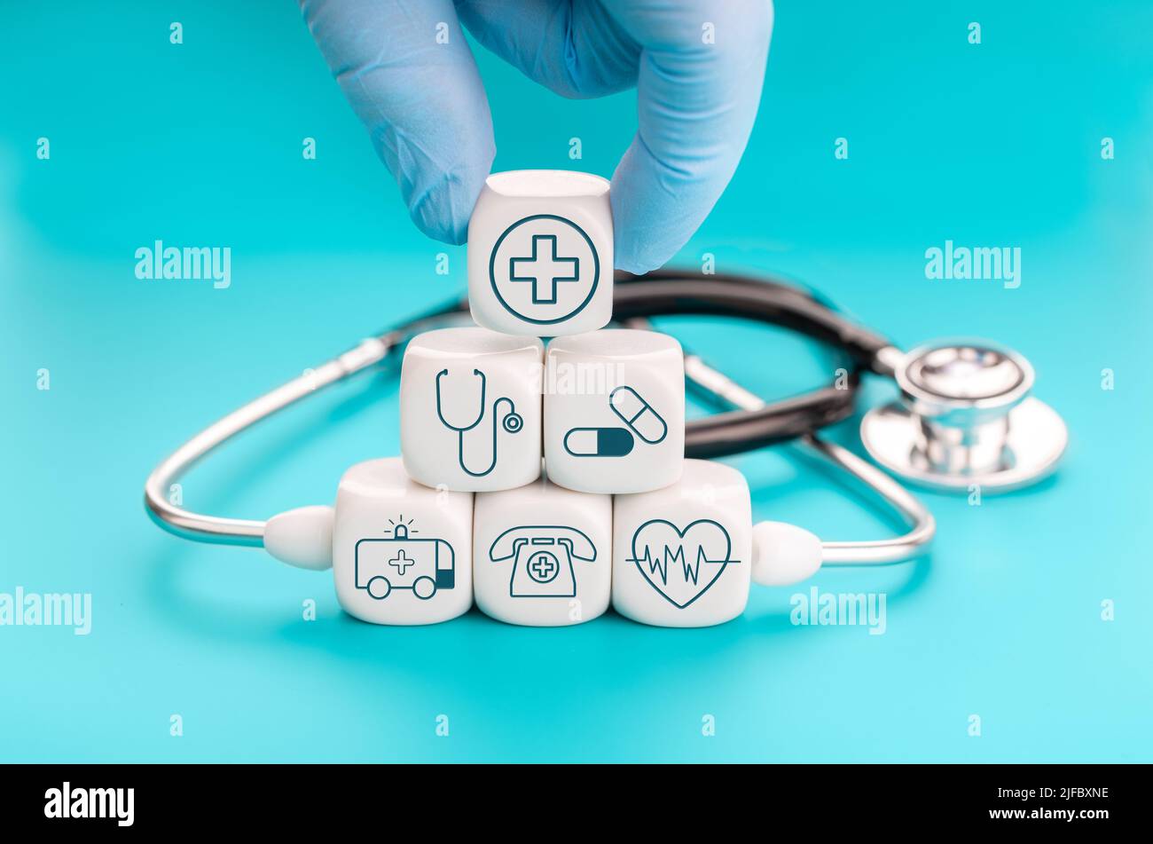Konzept der Krankenversicherung. Medizinische Symbole auf würfelförmigen Blöcken und Hand mit einem Block mit medizinischem Symbol Stockfoto