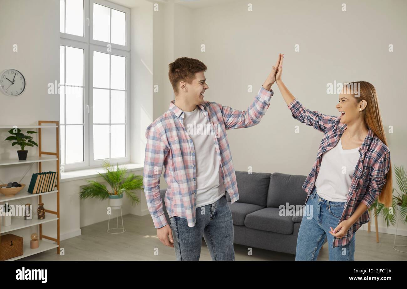 Glückliches, aufgeregtes junges Paar feiert den Kauf eines neuen Hauses und gibt sich gegenseitig hohe fünf Stockfoto