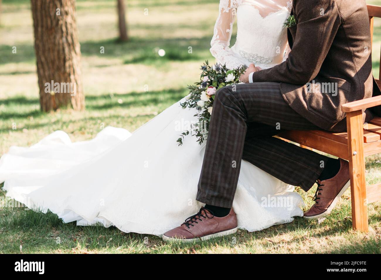 Braut und Bräutigam sitzen auf der Bank im park Stockfoto