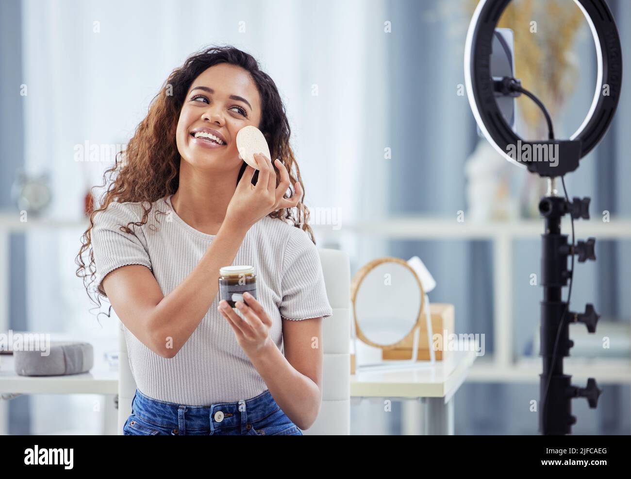 Eine hispanische Frau, die mit ihrem Telefon ein Make-up-Tutorial für ihren Beauty-Blog aufzeichnete, während sie zu Hause saß. afroamerikanische Influencerin live Stockfoto