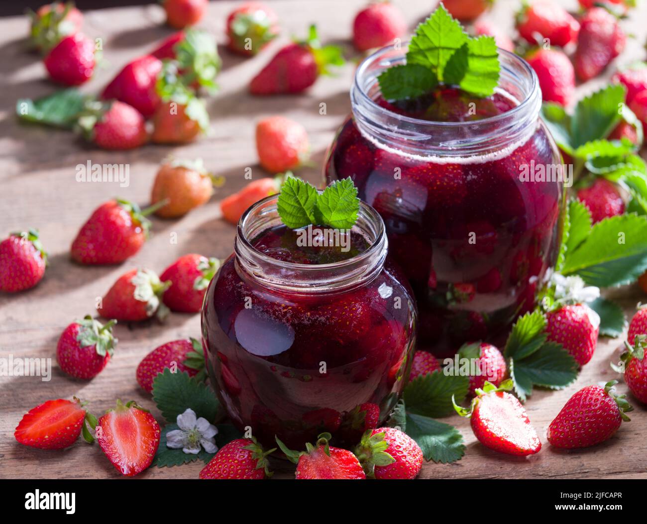 Hausgemachte Erdbeermarmelade. Erdbeeren und Marmeladenglas auf rustikalem Tisch. Frühlingsfrüchte. Stockfoto