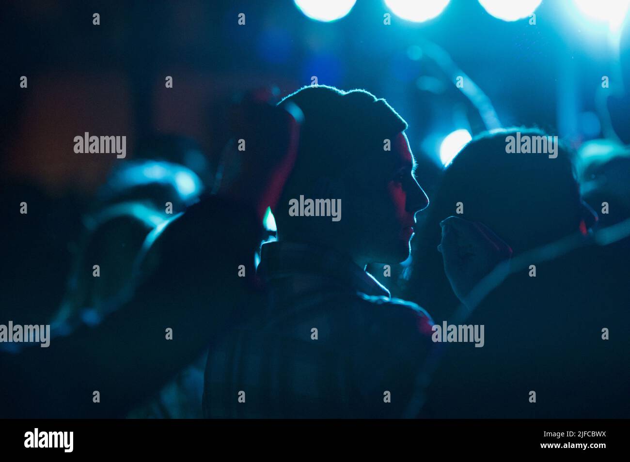 Eine Silhouette eines Mannes auf einer Party unter blauem Licht Stockfoto