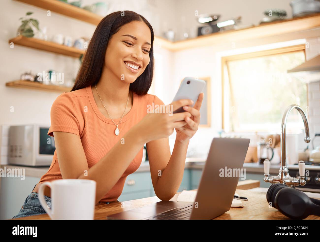 Junge schöne glückliche gemischte Rasse Geschäftsfrau mit einem Telefon, während der Arbeit von zu Hause aus. Content hispanic Frau mit Social Media auf ihrem Handy, während Stockfoto