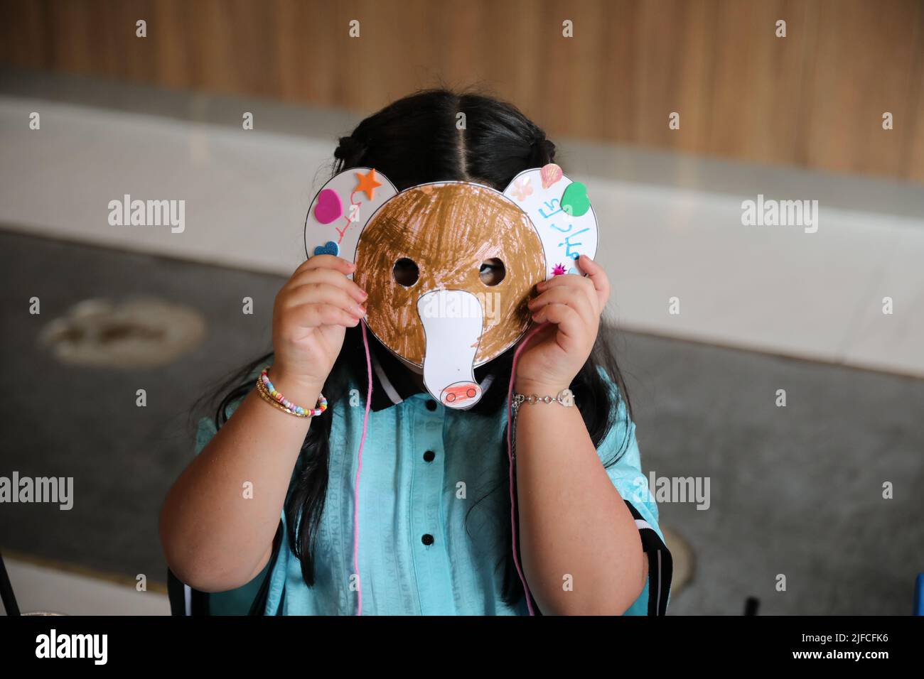 Kleines Mädchen trägt eine bunte Tier Papiermaske vor ihrem Gesicht, Elefantenmaske Handwerk. Stockfoto