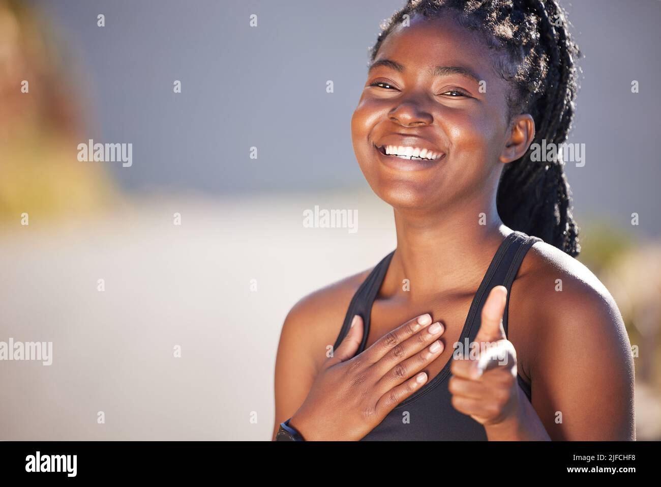 Eine glückliche junge, fit afroamerikanische Frau, die allein steht und zeigt, während sie sich nach einem Training sicher fühlt. Fit und aktive schwarze Frau mit Zöpfen Stockfoto