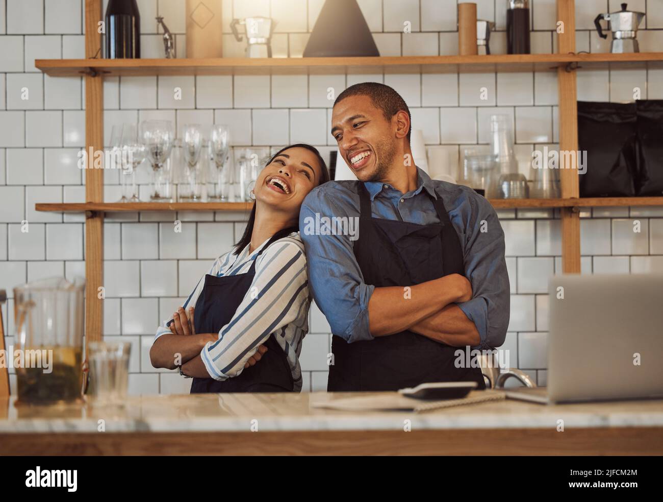 Fröhliche Geschäftsleute, die in ihrer Cafeküche stehen. Geschäftspartner stehen in ihrem Coffeeshop zurück an den Rücken. Zwei Unternehmerarme kreuzten sich Stockfoto