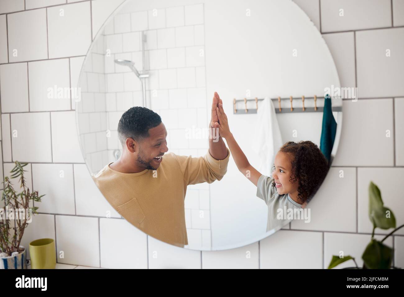 Fröhliche Mischvaters Vater und Tochter waschen sich die Hände in einem Badezimmer zu Hause. Ein einziger afroamerikanischer Elternteil unterrichtet seine Tochter davon Stockfoto