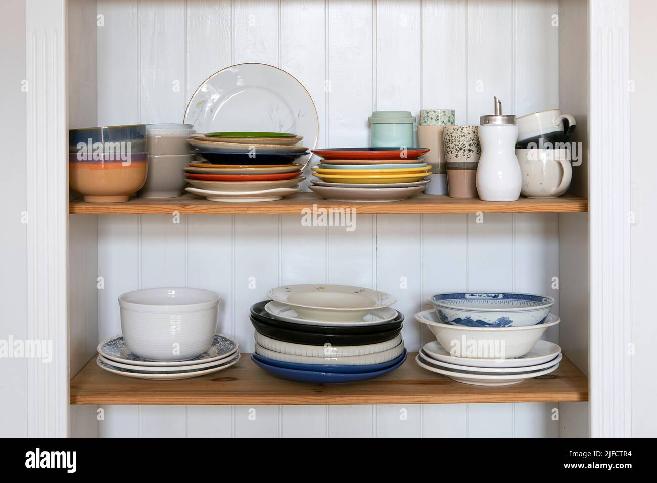 Schrank Regal aus Holz mit Küchenutensilien, rustikalen Stil. Geschirr, Teller und Tassen stehen auf einem Regal in der Küche. Schrank mit Satz von bunten d Stockfoto
