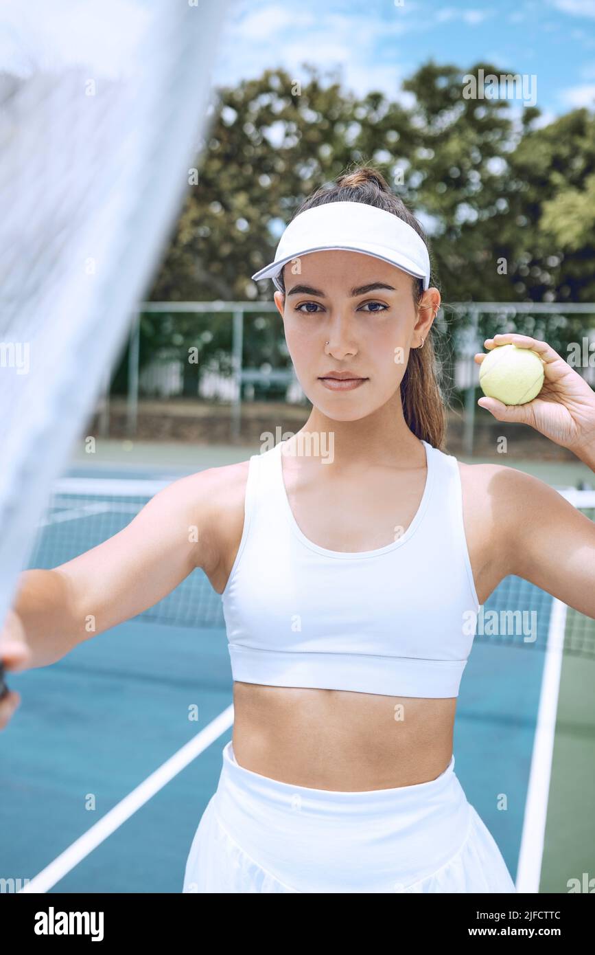 Selbstbewusste junge Tennisspielerin mit Tennisschläger und Ball. Hispanische Frau bereit für ihr Tennisspiel im Club. Sportlerin bereit für Stockfoto