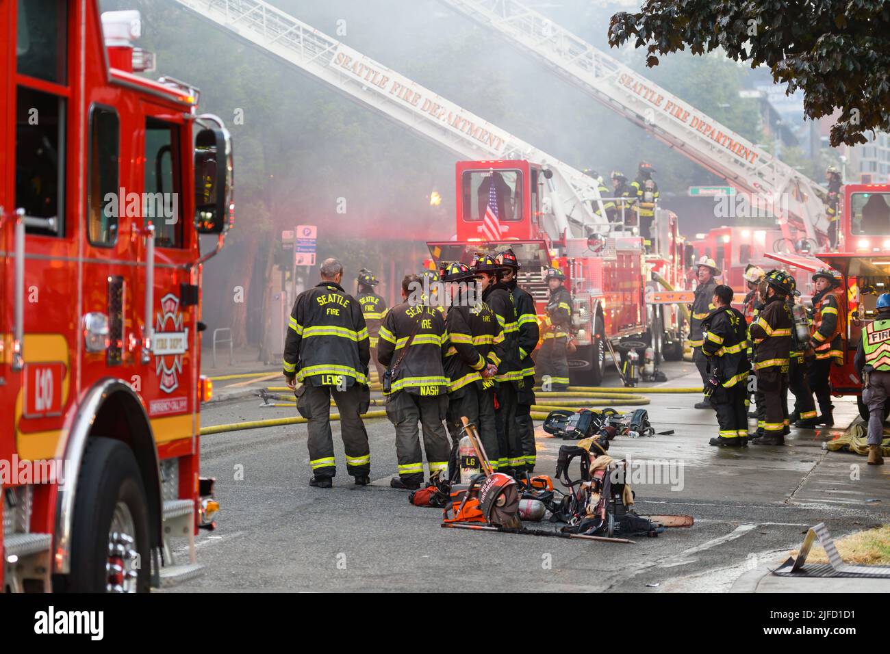 Seattle - 30. Juni 2022; Feuerwehr-Teams der Stadt Seattle warten mit Leiterwagen, die in einem instabilen Gebäude in der Nachbarschaft von Belltown einen Brand auslössen Stockfoto