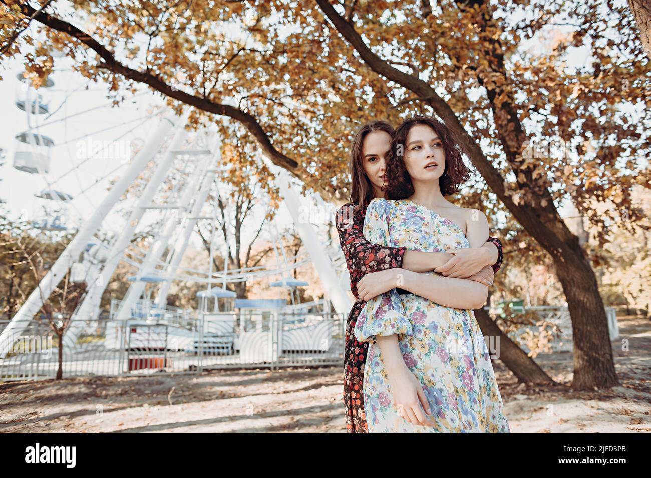Zwei junge Frauen in Vintage-Kleidern stehen im Herbst umarmt parken Stockfoto