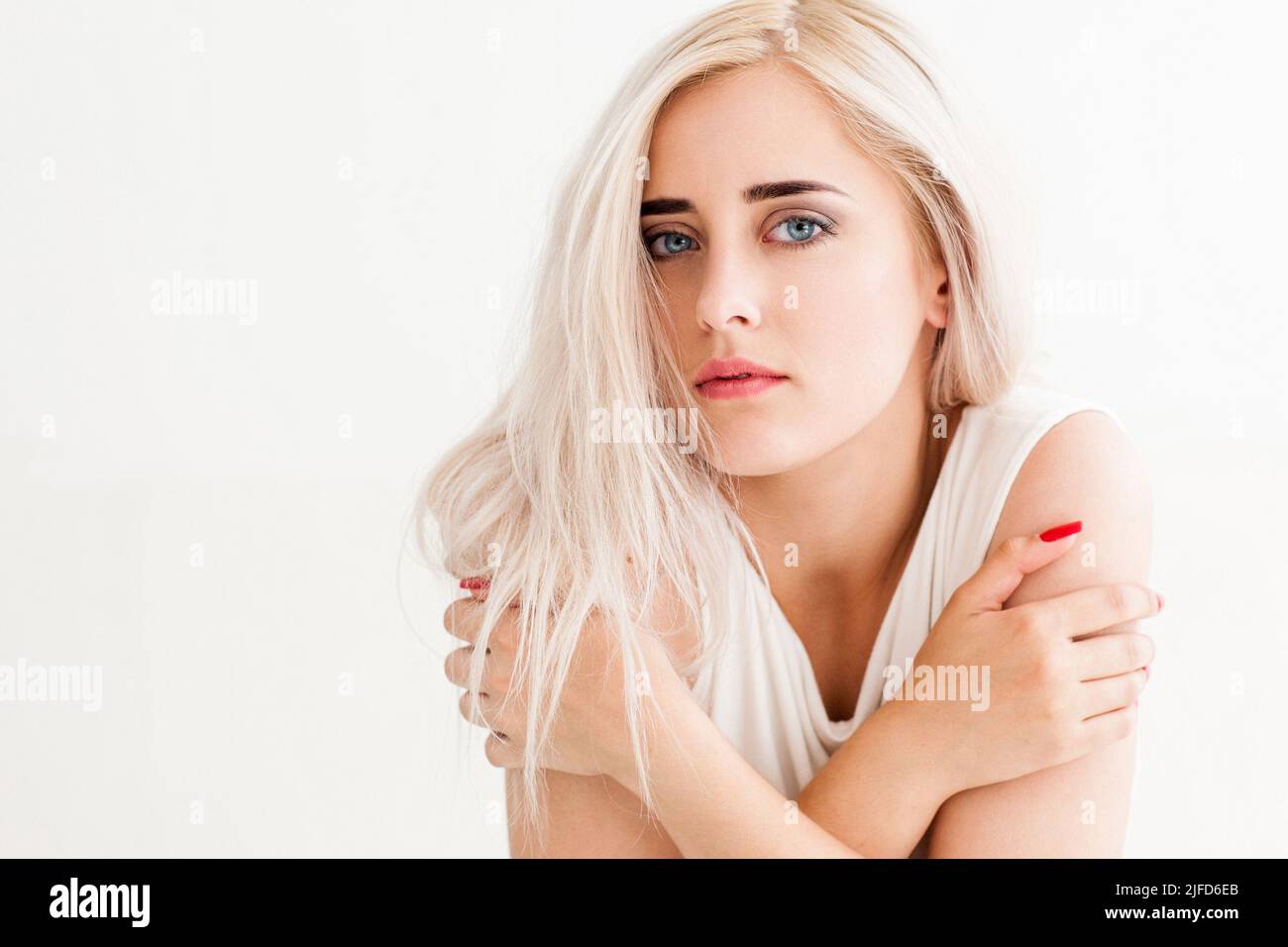 Attraktive gefrorene Blondine umarmt sich selbst. Stockfoto