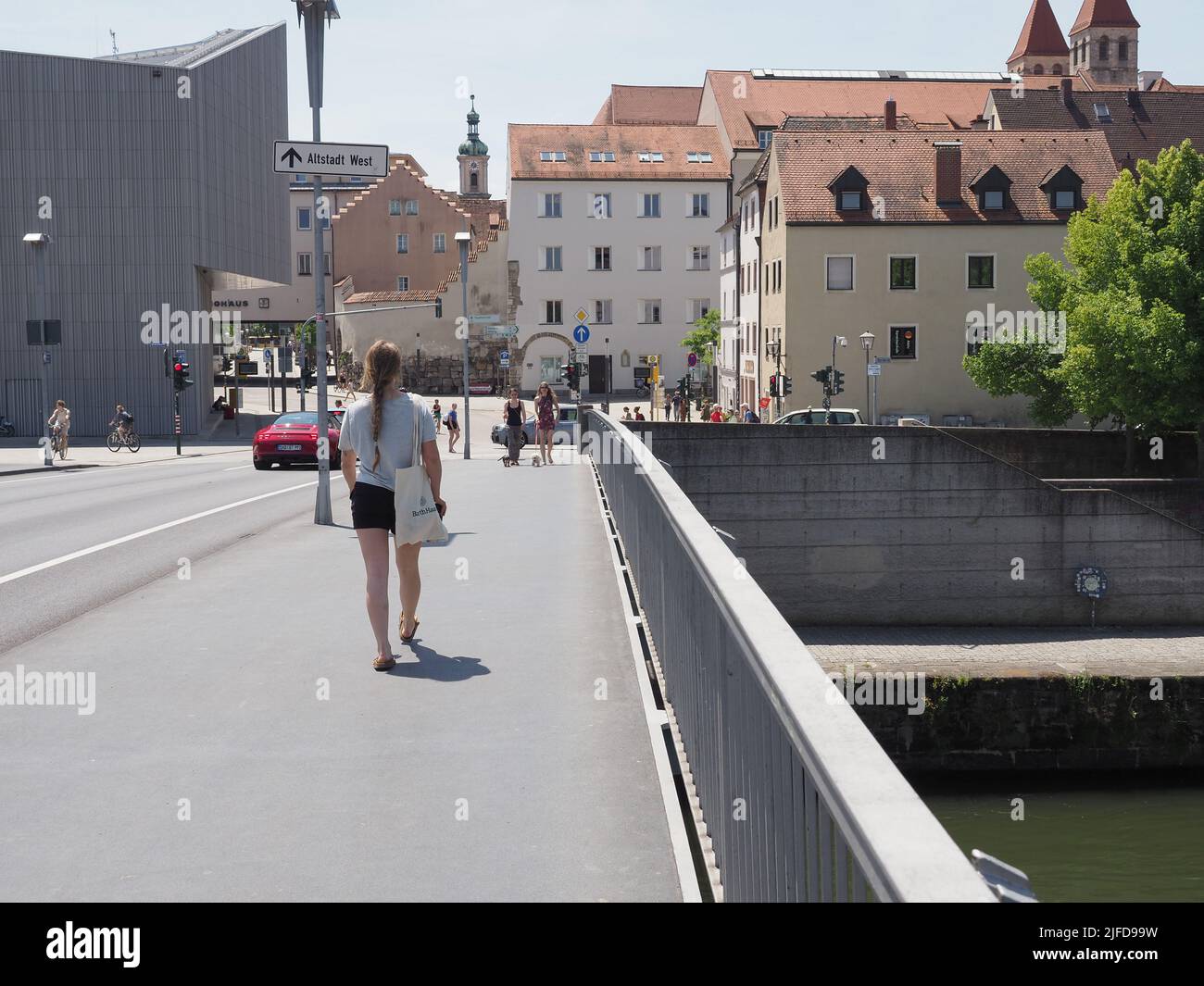 REGENSBURG, DEUTSCHLAND - CA. JUNI 2022: Menschen überqueren die Eiserne-Brücke über die Donau Stockfoto