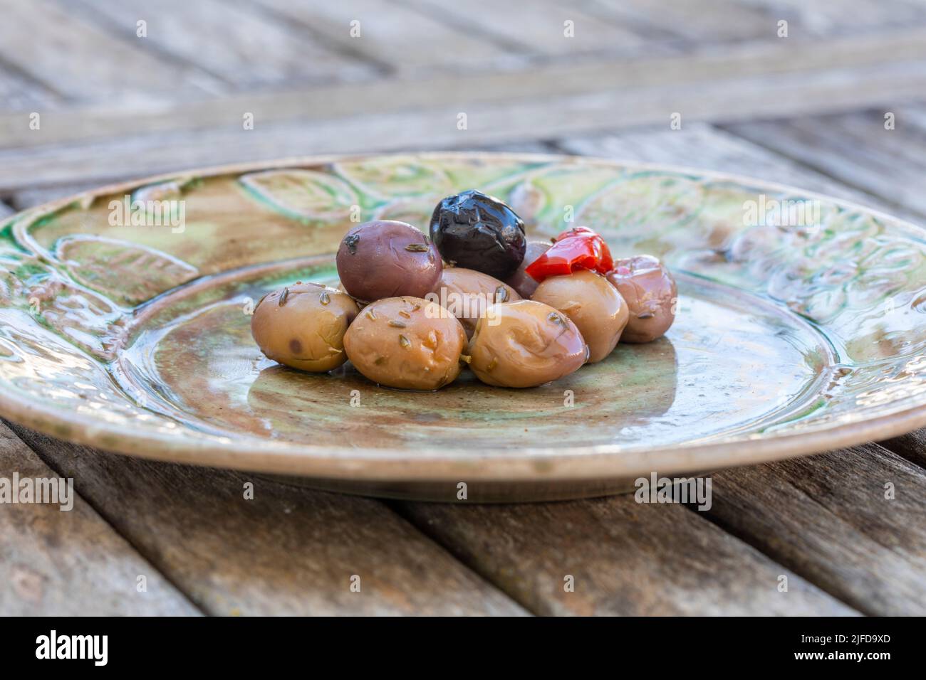 Ein grüner Teller mit gemischten Oliven darauf. Stockfoto